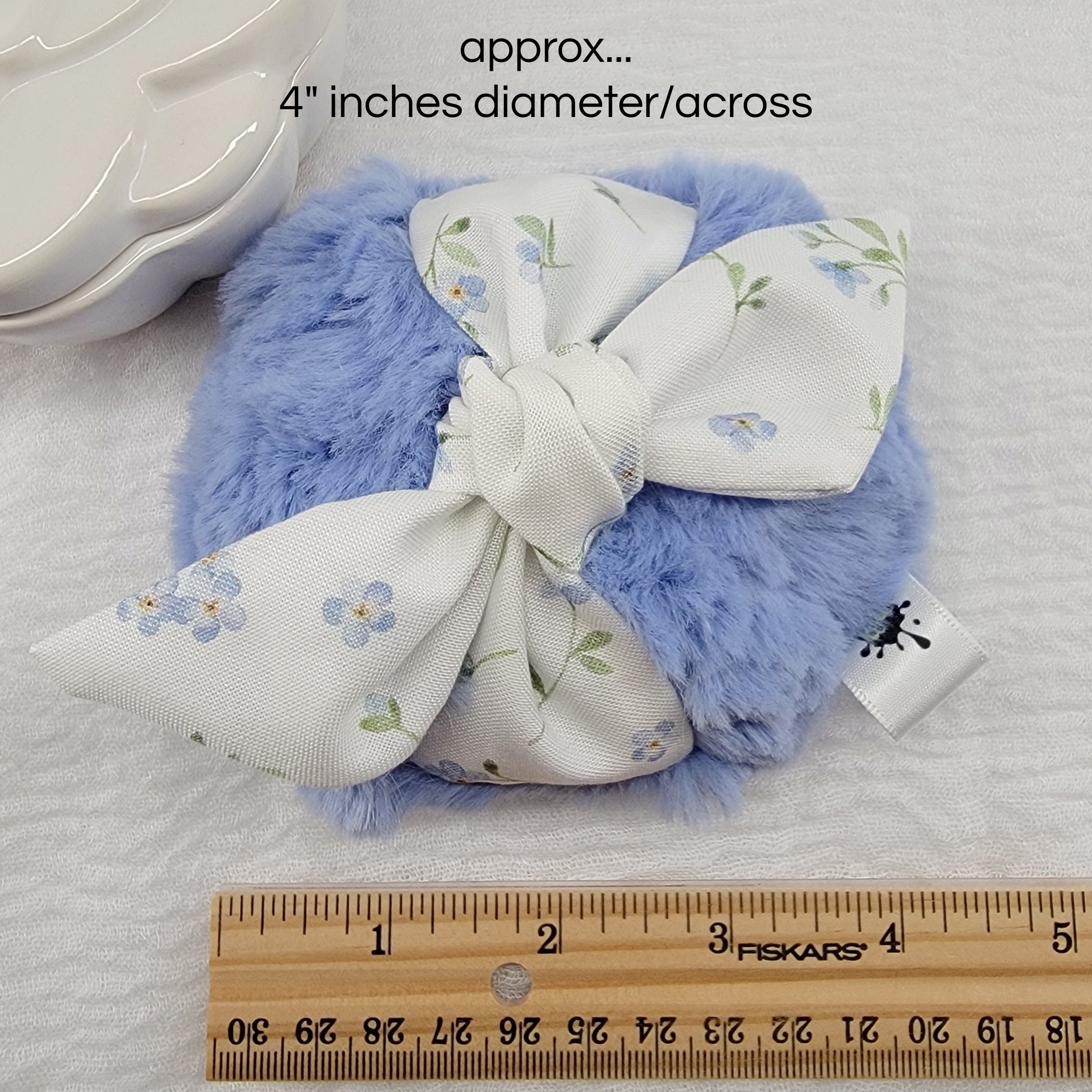 soft blue body powder puff with tiny blue flowers. Measures 4 inches across.