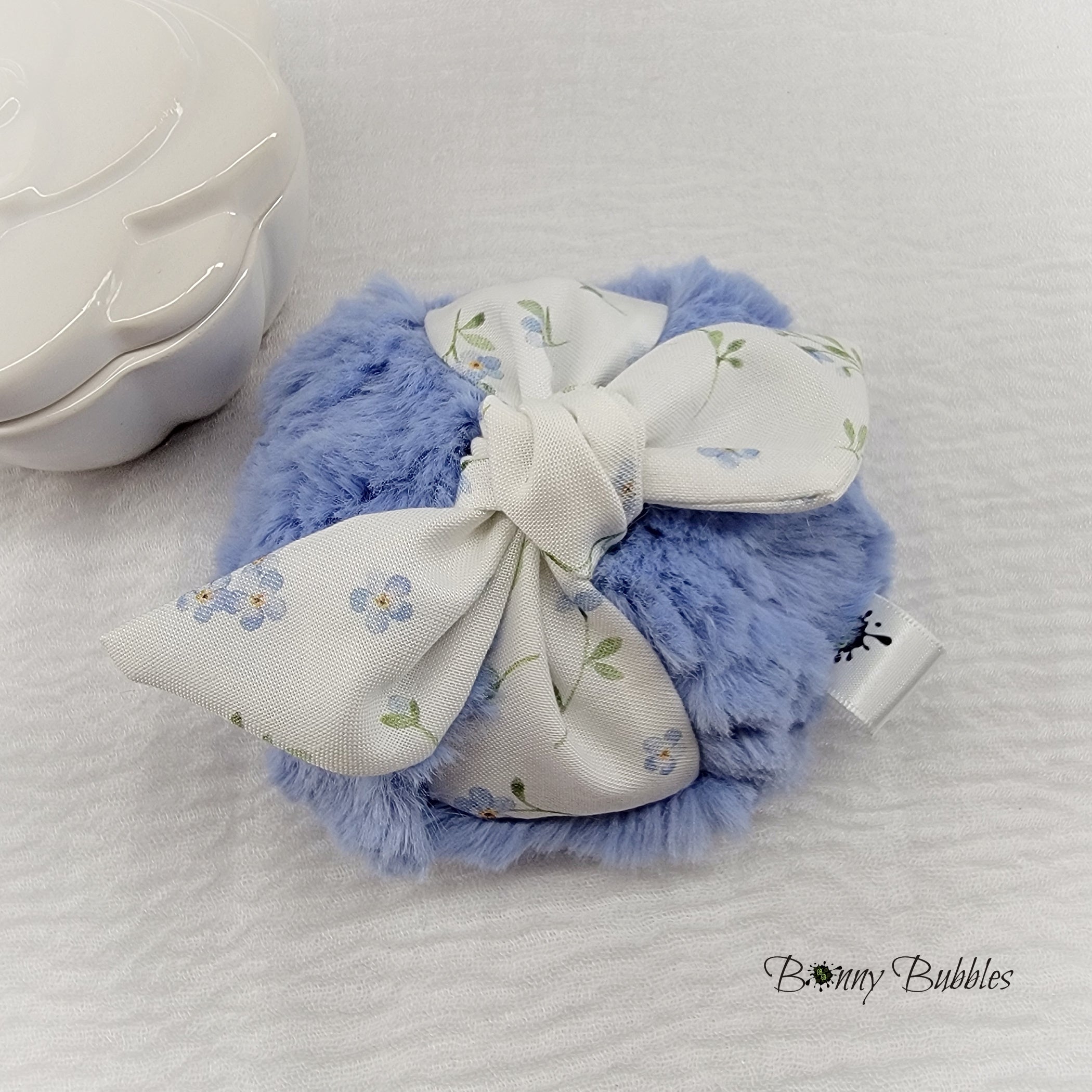 soft blue body powder puff with tiny blue flowers. Measures 4 inches across.